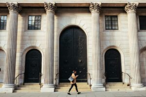 woman walking in-front of white building with ionic pillars