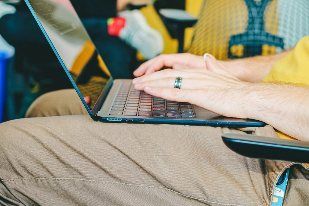 Hands typing on a laptop keyboard with a ring.