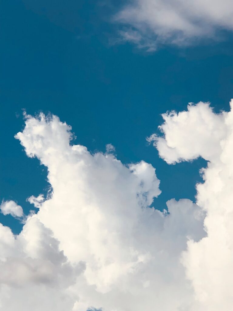 A plane flying through a blue cloudy sky